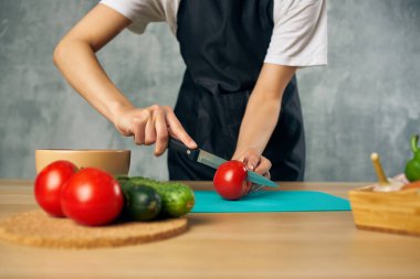 Ev hanımı mutfakta sebze kesme tahtası kesiyor.