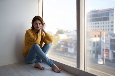 Güzel bir kadın evdeki pencere eşiğinde yatıyor.