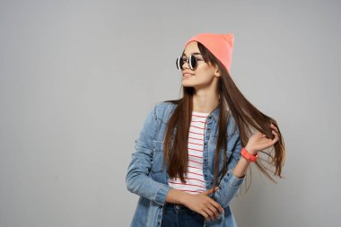 Güneş gözlüklü, pembe şapkalı bir kadın stüdyo tarzı poz veriyor.