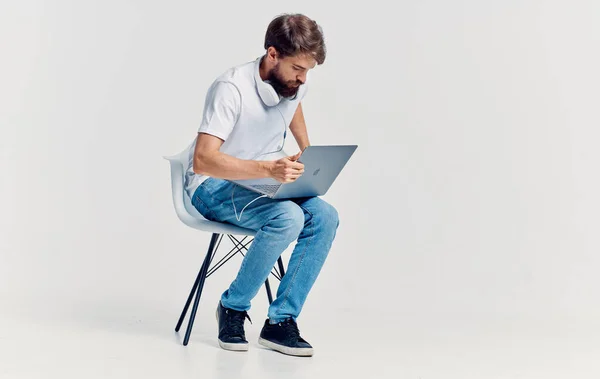 young man sitting on a chair with a laptop in headphones technology