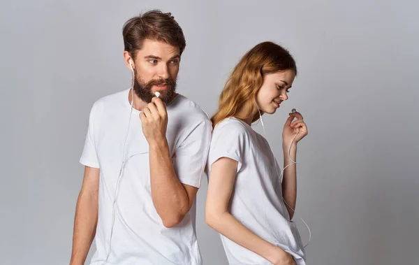 Hombre y mujer en camisetas blancas están de pie junto a la música de la amistad en los auriculares — Foto de Stock