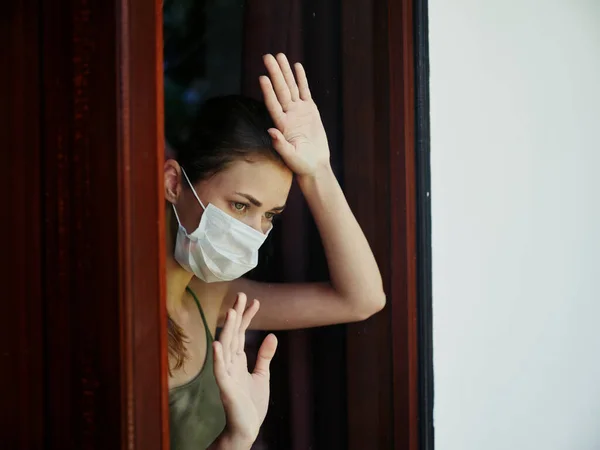 Mujer con máscara médica asomándose por la ventana de cierre —  Fotos de Stock