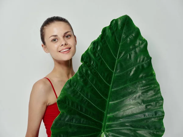 Γυναίκα σε ένα κόκκινο μαγιό ελκυστική εμφάνιση πράσινο φύλλο — Φωτογραφία Αρχείου