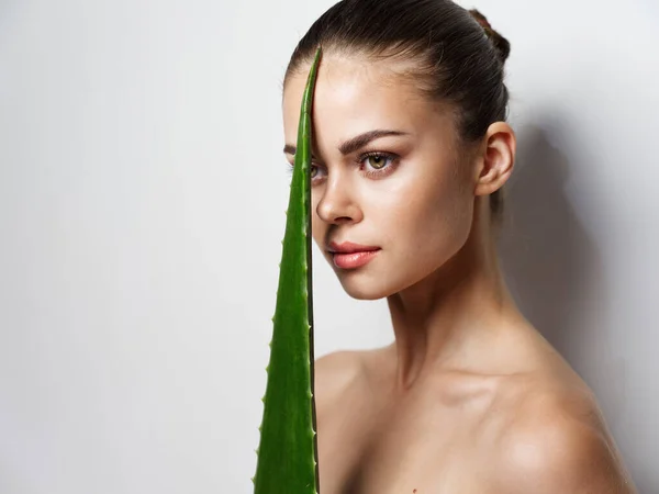 Bela mulher com folha de aloés verde na frente de seu rosto fagópiro nu — Fotografia de Stock