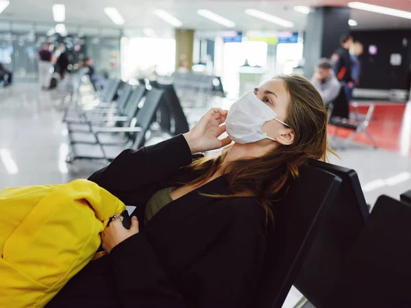 Женщина в медицинской маске сидит в багаже аэропорта ожидая — стоковое фото