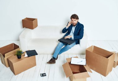 Kanepede kutuları taşıyan bir iş adamı. Yeni iş yerleri taşınıyor.