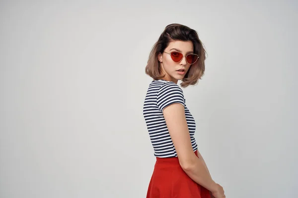 Mujer emocional con gafas de sol falda roja hojalata manos fondo claro — Foto de Stock