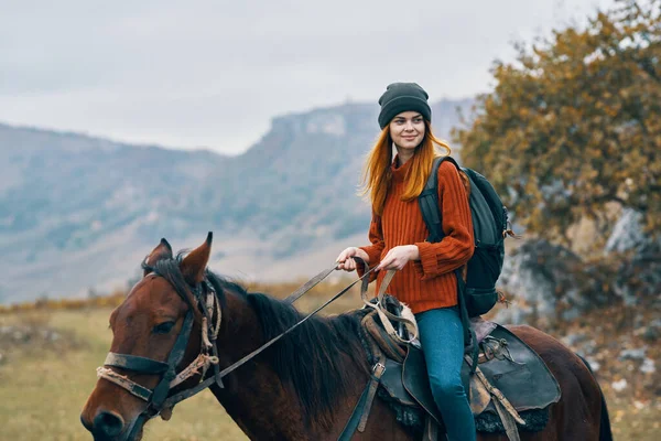 Mulher caminhante monta um cavalo na natureza nas montanhas — Fotografia de Stock