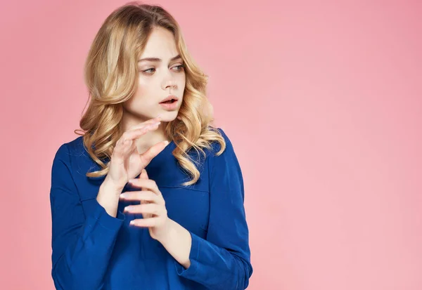 Fröhliche hübsche Frau in einem blauen Kleid auf rosa Hintergrund — Stockfoto