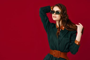 Güzel bir kadın saç ceketi tutuyor. Kırmızı arka plan.