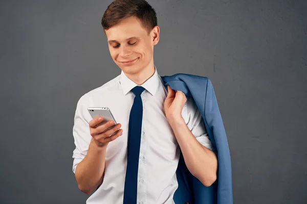 Ein Mann im Hemd mit Krawatte und Telefon in der Hand Büroarbeit dunkler Hintergrund — Stockfoto