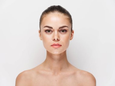 Çıplak omuzlu genç bir kadının portresi. Açık tenli, saç stili, doğal görünümlü.