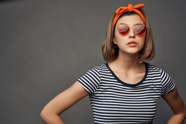 Femme à la mode portant des lunettes de soleil rayé t-shirt style de vie glamour fond sombre — Photo