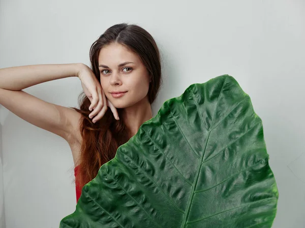 Mulher segurando mão perto de rosto folha de palma charme luz fundo — Fotografia de Stock