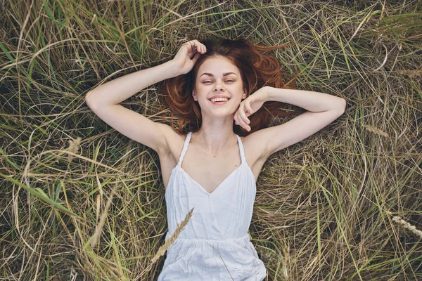 Una mujer en un vestido blanco se encuentra en la naturaleza hierba relajación sol vista superior —  Fotos de Stock