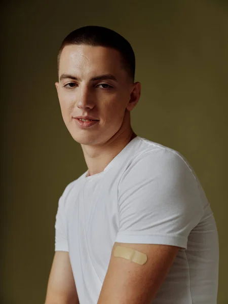 Handsome man in white t-shirt with adhesive plaster on his shoulder infection immunity safety immunization — Stock Photo, Image