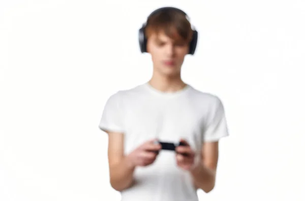 Chico en camiseta blanca con auriculares jugando videojuegos — Foto de Stock