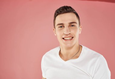 Beyaz tişörtlü gülümseyen adam kırpılmış pembe arka plan çekici görünümü