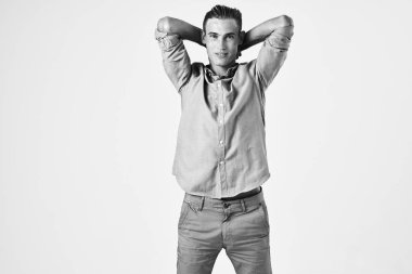 Havalı saç stili olan yakışıklı bir adam ellerini arka planda tutarak poz veriyor.