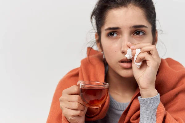 Frau zu Hause mit einer Tasse Tee bedeckt mit einer kalten Decke — Stockfoto