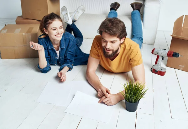 Un hombre y una mujer yacen en el suelo cajas móviles nueva vivienda — Foto de Stock