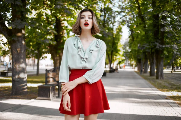 Vacker kvinna i röd kjol i parken promenad livsstil frisk luft — Stockfoto