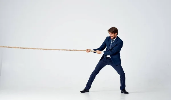 Business man in a suit pulls the rope studio light background — Stock Photo, Image