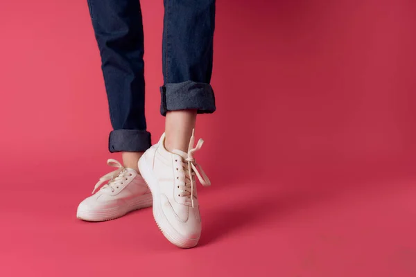 Перевернутые женские ноги в белых кроссовках розовый фон обрезанный вид студии — стоковое фото