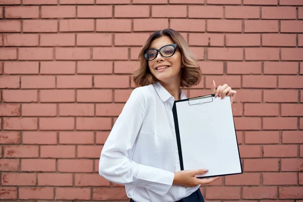 Obchodní žena manažer brýle papírování cihlová zeď na pozadí — Stock fotografie