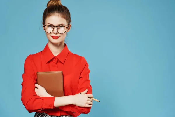 Nő egy piros ingben egy notebook a kezében üzlet úgy néz ki, professzionális munka — Stock Fotó