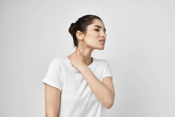 Brunette in a white t-shirt holds on to the neck treatment — Stock Photo, Image