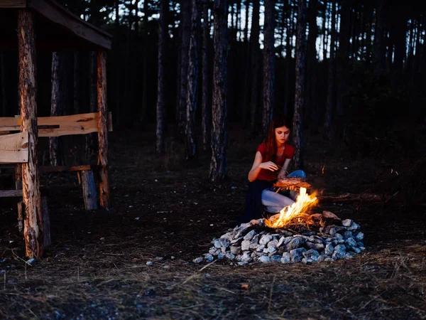 Vrouw zit in de natuur bij het kampvuur rust bos — Stockfoto