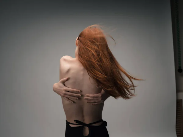 Rödhårig kvinna som håller händerna bakom ryggen visa figur — Stockfoto