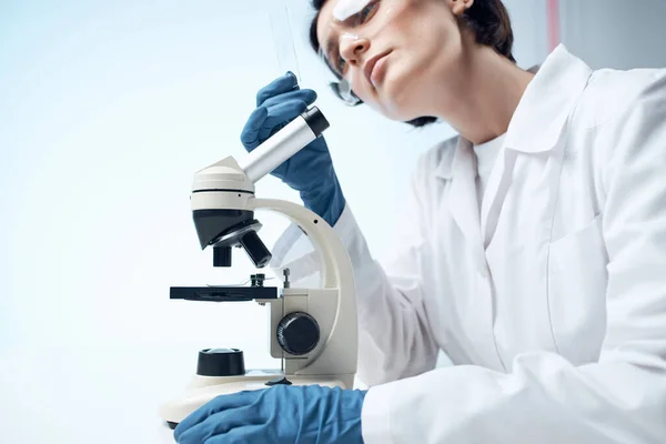 Donna scienziata in un mantello bianco guardando attraverso uno studio al microscopio — Foto Stock