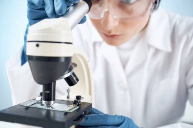 Tıbbi eldivenler mikroskop biyoteknoloji tıbbında kadın laboratuvar asistanı.