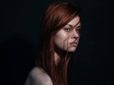 Güzel, kızıl saçlı, çıplak omuzlu, yakın plan koyu renk arka plan.