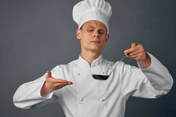 Chef in accappatoio bianco con un mestolo in mano cucinare cibo ristorante — Foto Stock