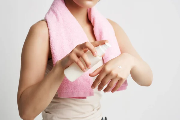 Donna con asciugamano rosa applica lozione sulla cura del corpo della mano — Foto Stock