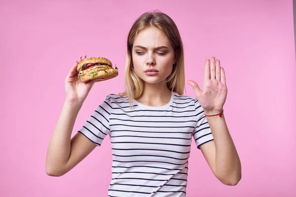 Vidám nő gyors ételek a kezében snack finom rózsaszín háttér — Stock Fotó