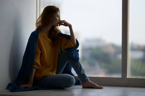 Vrouw zitten op de vensterbank met een blauwe ruit glimlach — Stockfoto