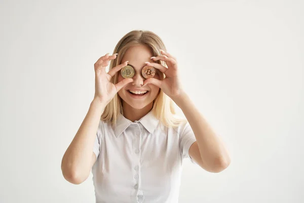 Vrolijk blond in een wit shirt met Bitcoin cryptogeld in de buurt van haar ogen — Stockfoto