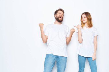 Beyaz tişörtler ve kot pantolon stüdyosu içinde açık arka plan pozu veren neşeli genç çift.