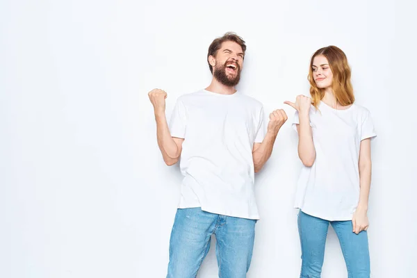 Cheerful young couple in white t-shirts and jeans studio posing light background — Stock Photo, Image