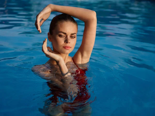Женщина в купальнике держит руки над головой в роскошном бассейне — стоковое фото