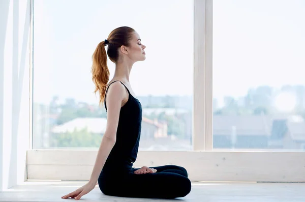 Mujer sentada en posición de loto ejercicio meditación yoga cerca de ventana — Foto de Stock
