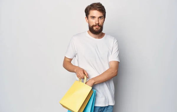 Um homem em uma camiseta branca com pacotes em suas mãos andando estilo de vida de entretenimento — Fotografia de Stock