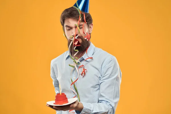 Vidám férfi egy pólóban sapkával a fején torta ünneplés Születésnapi konfetti — Stock Fotó