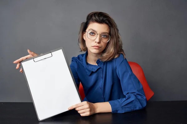 Жінка в синій сорочці сидить за столом папка в її руках документи — стокове фото