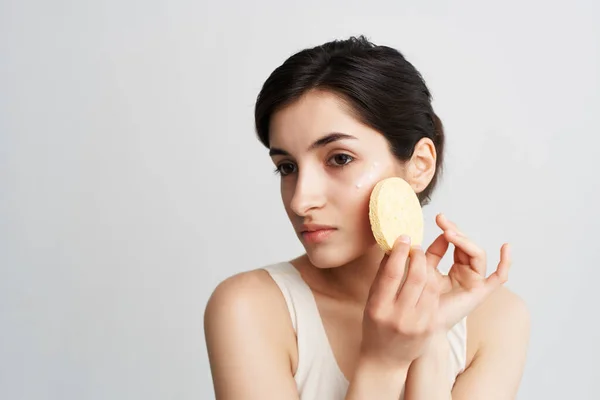 Morena aplica una crema de esponja en su cara piel limpia —  Fotos de Stock