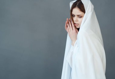 Kadın beyaz kumaş cazibesiyle kendini gizliyor.